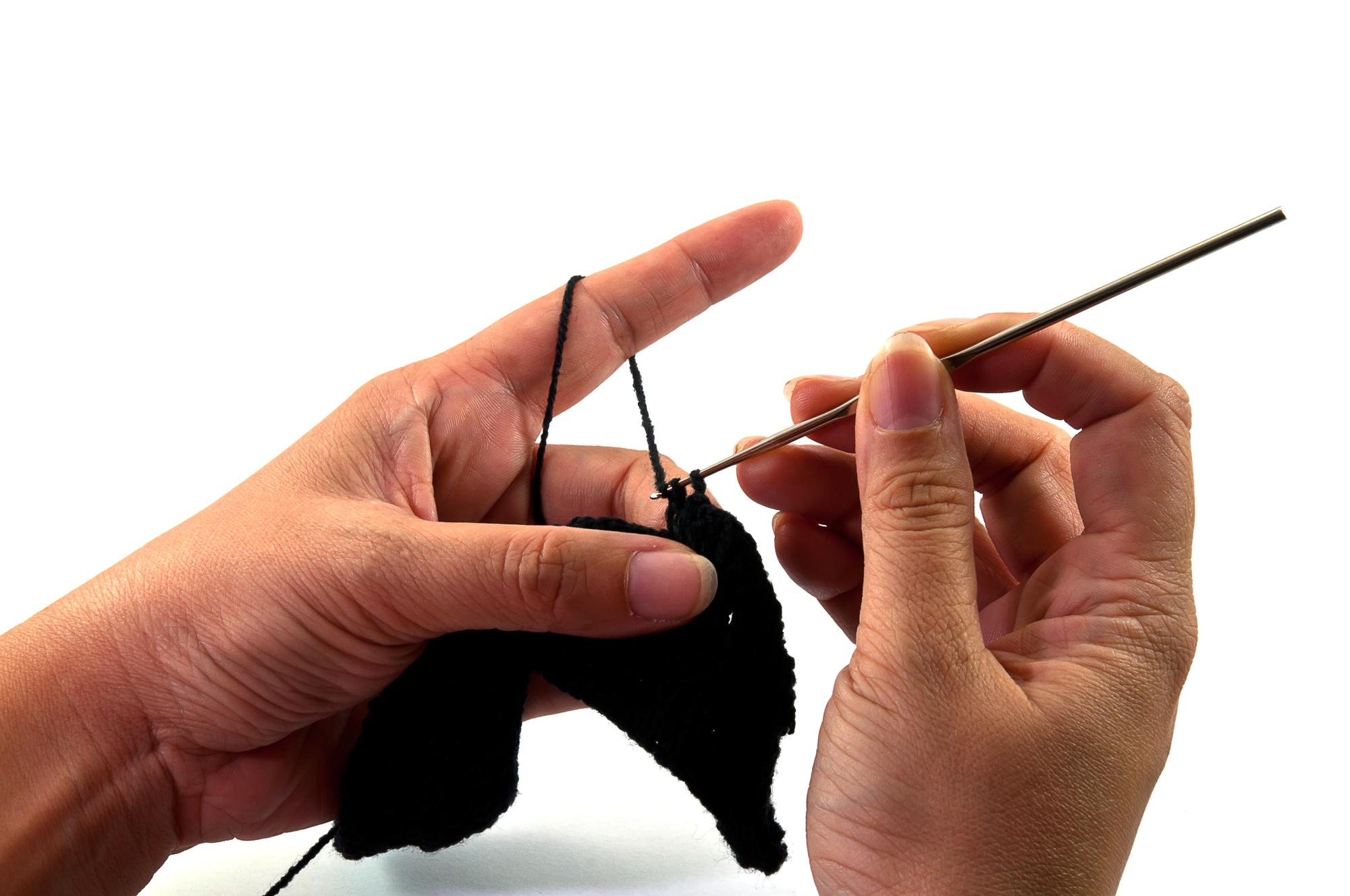 Hands holding needle and thread over cloth